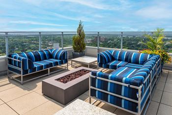 A patio with blue and white striped couches and a fire pit at Two Twelve Clayton Apartments, Clayton, MO, 63105